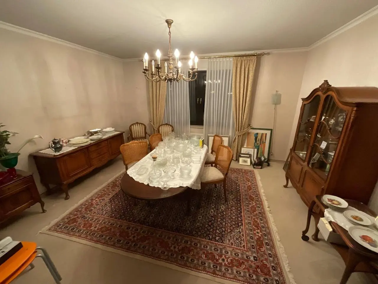 Esszimmer mit Kronleuchter, Vitrine und gedecktem Tisch vor dem Aussortieren