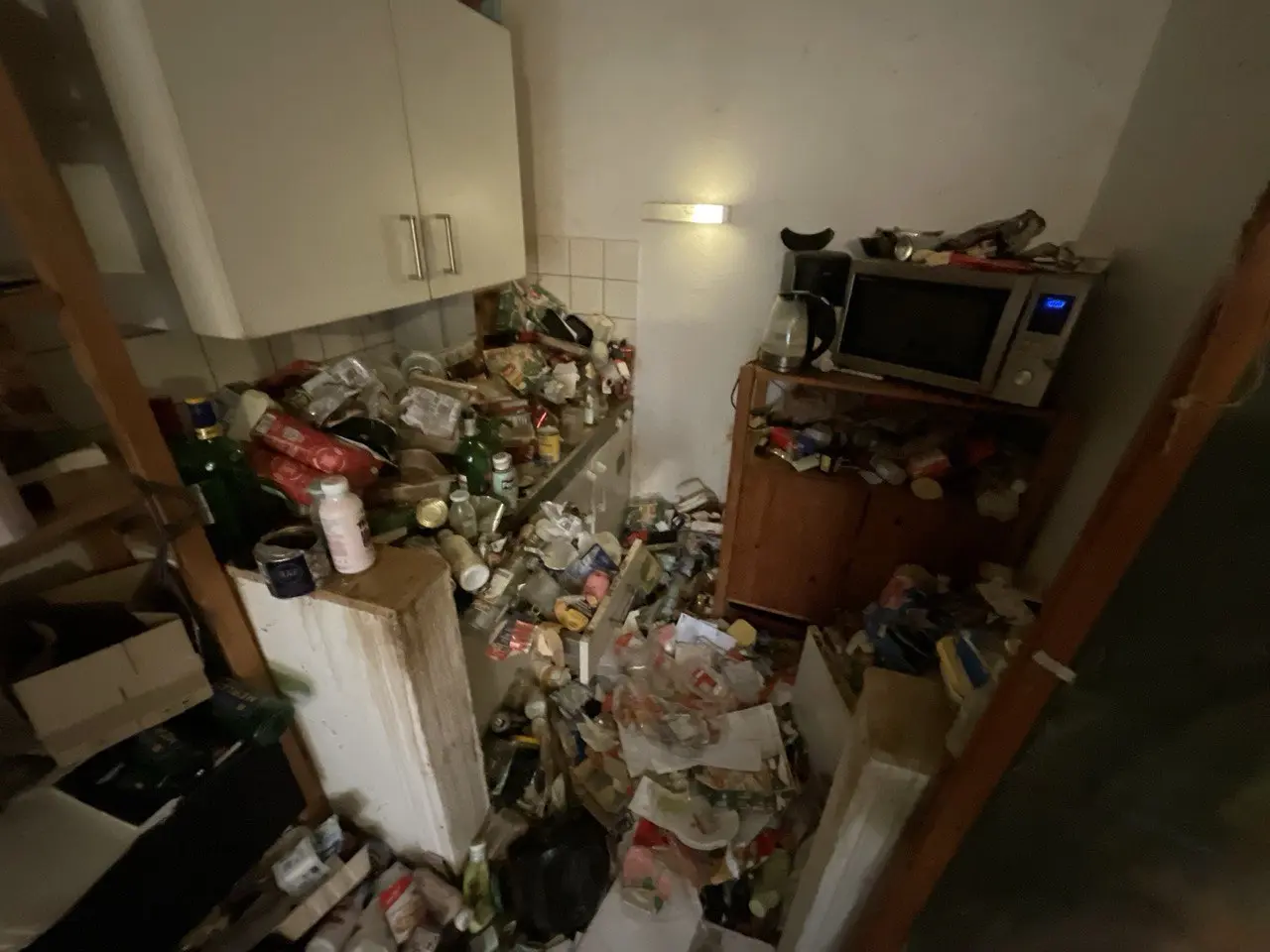Küche mit viel Hausrat auf Arbeitsflächen und Boden vor der Räumung