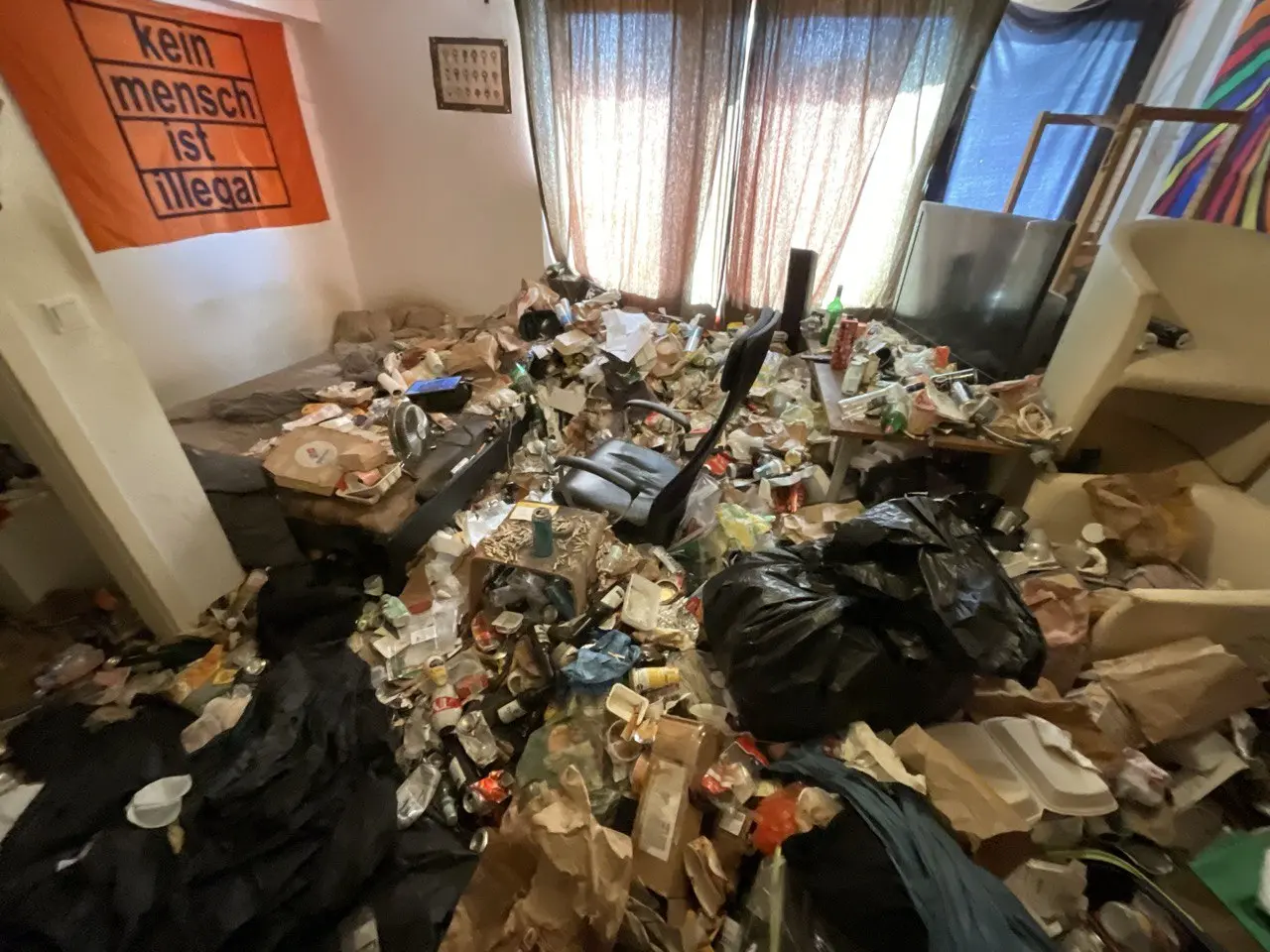 Wohnzimmer voller zurückgelassener Gegenstände und Müllsäcke