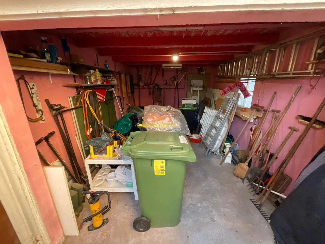Garage mit Werkzeugen, Regalen und einer Mülltonne