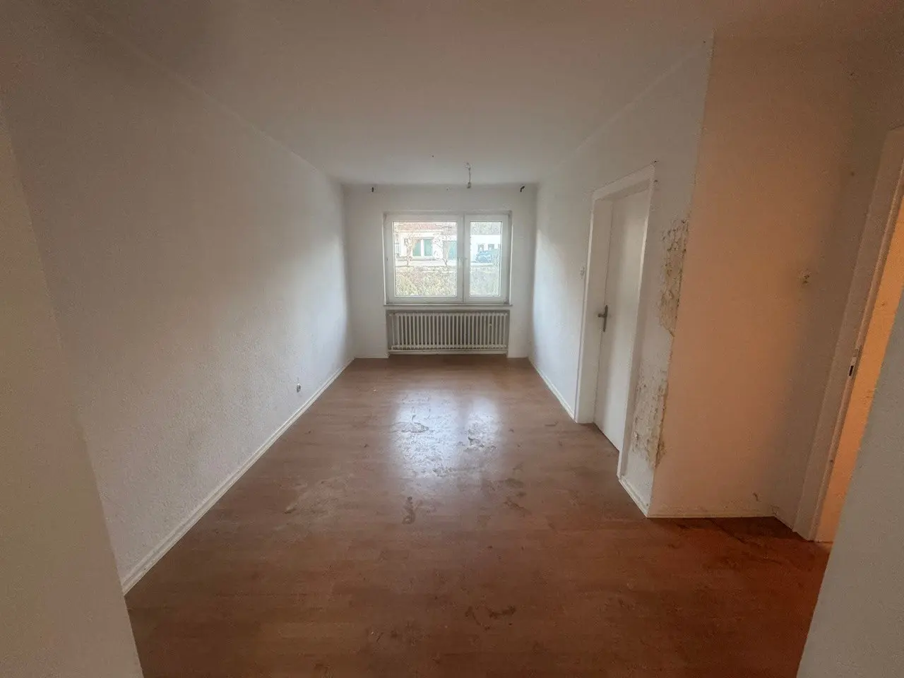 Geräumtes Zimmer mit Holzdielenboden nach dem Auszug