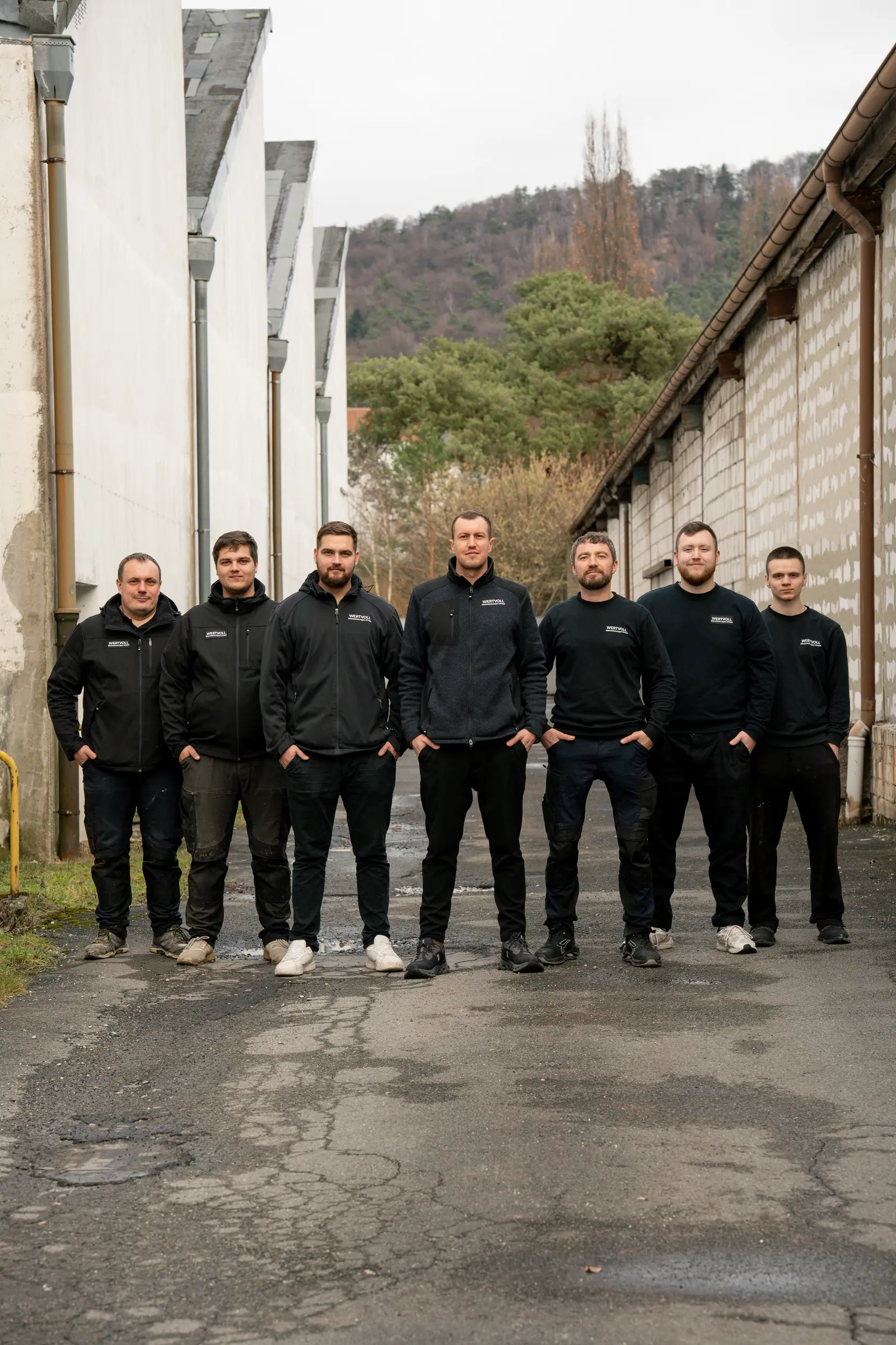 Das Team der Wertvoll Dienstleistungen GmbH in schwarzer Arbeitskleidung vor einer Hausfassade