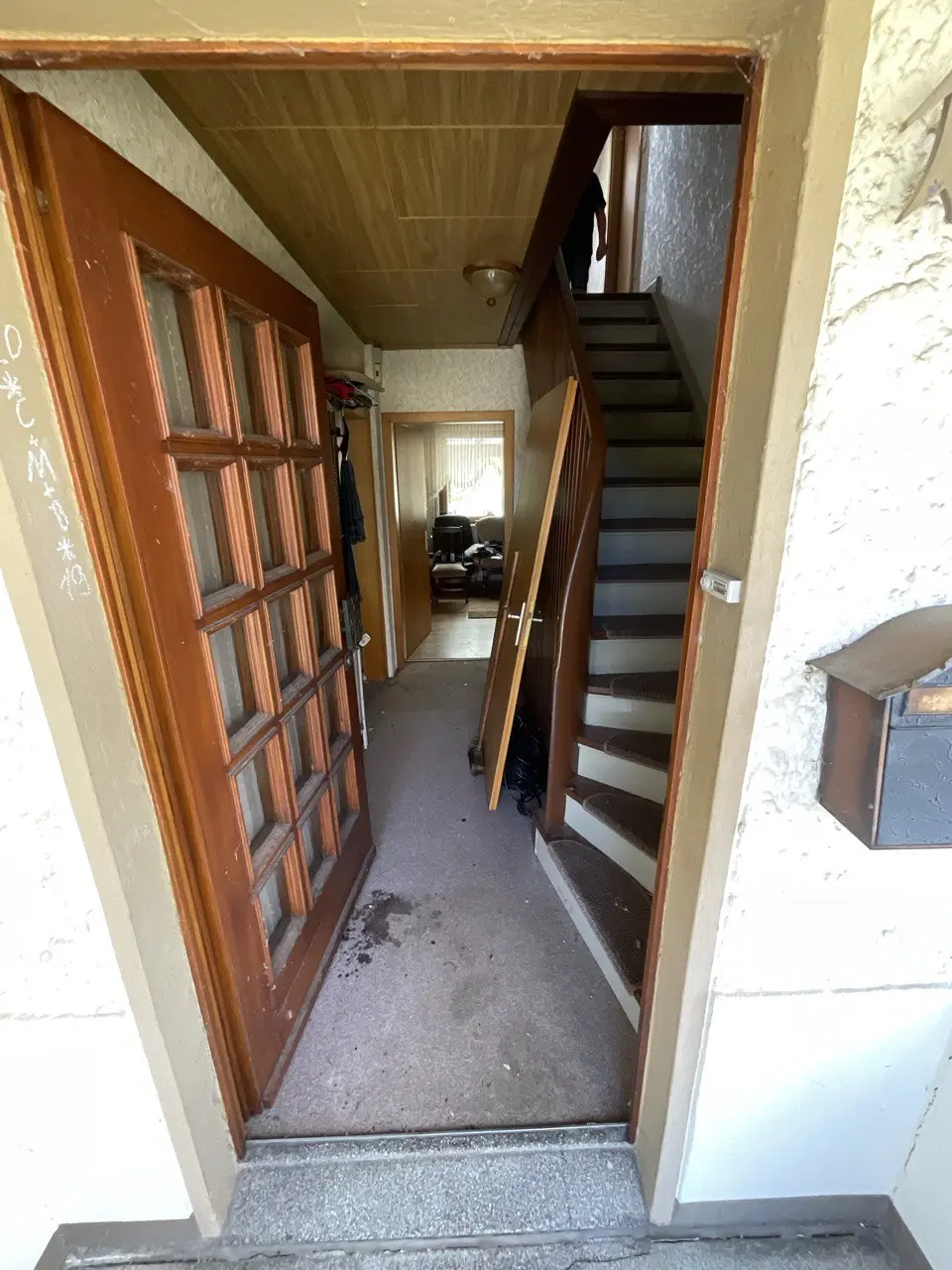 Geöffnete Holztür mit Treppe zum Dachboden, der mit geräumt wird