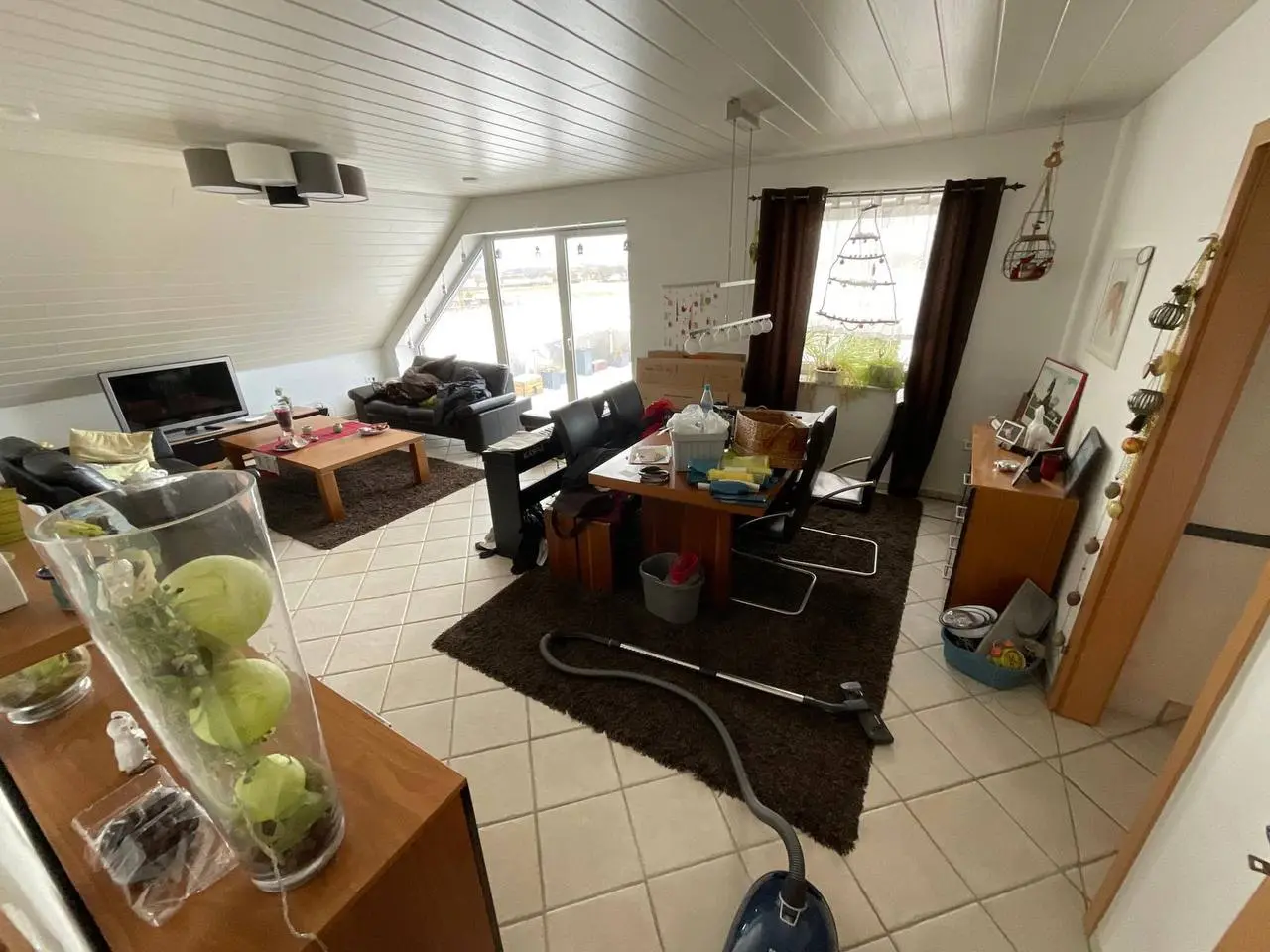 Wohnzimmer mit Dachschräge, Sofa und Regalen, in dem aussortiert wird