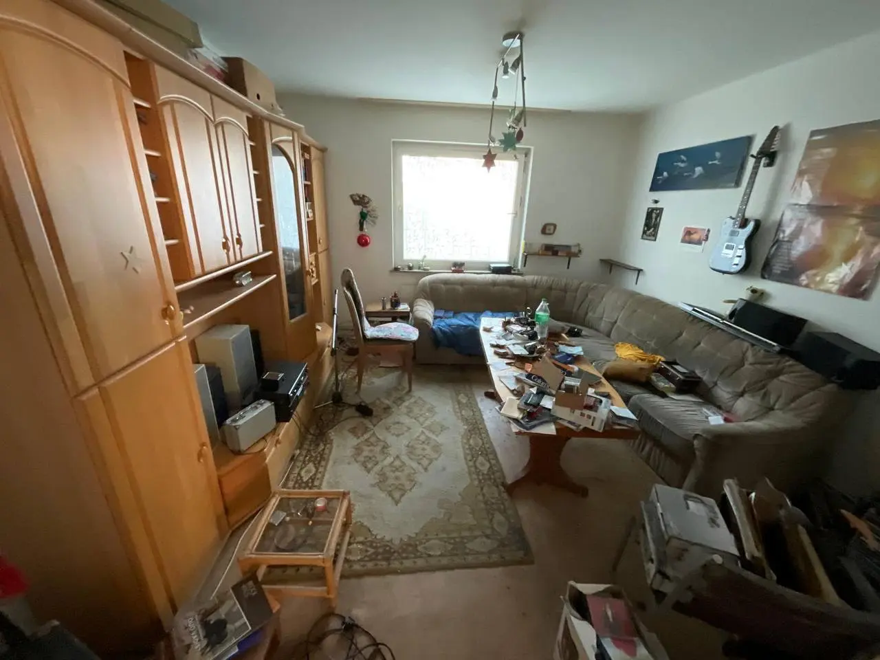 Eingerichtetes Wohnzimmer mit großer Holzschrankwand, Sofa und Couchtisch